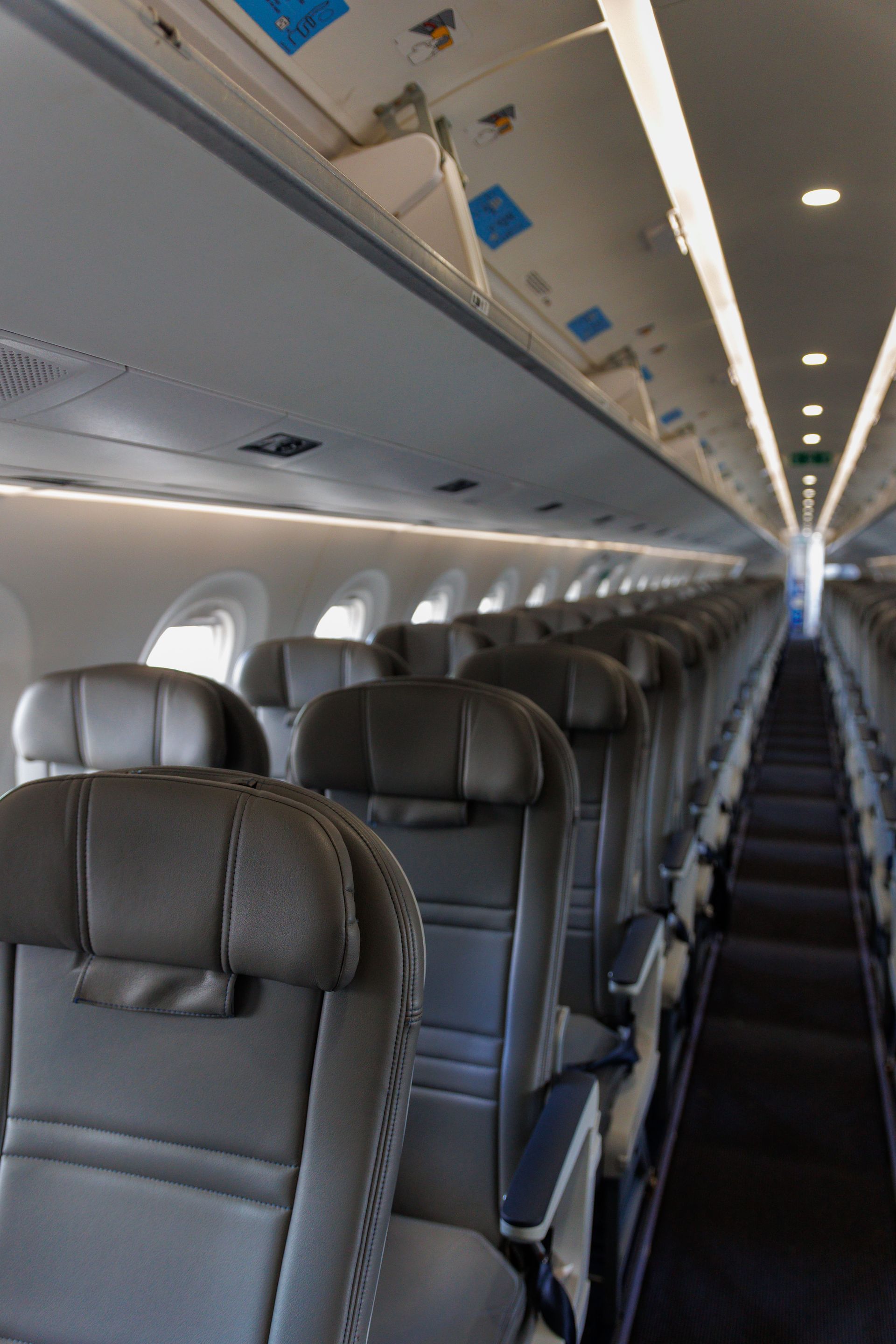 Interior view of an empty airplane cabin featuring rows of leather seats and overhead compartments.