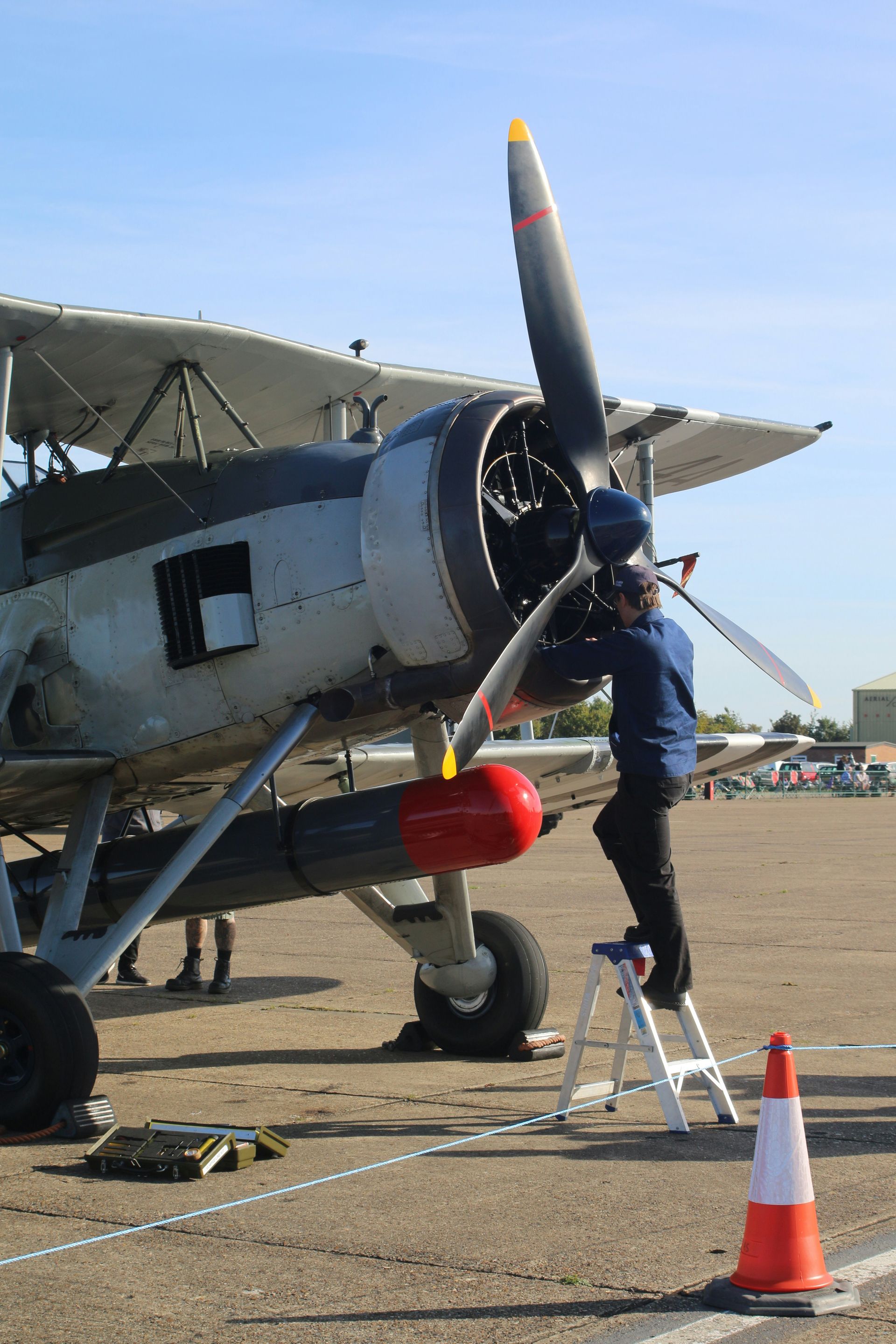 Mechanic works on an old biplane's engine.