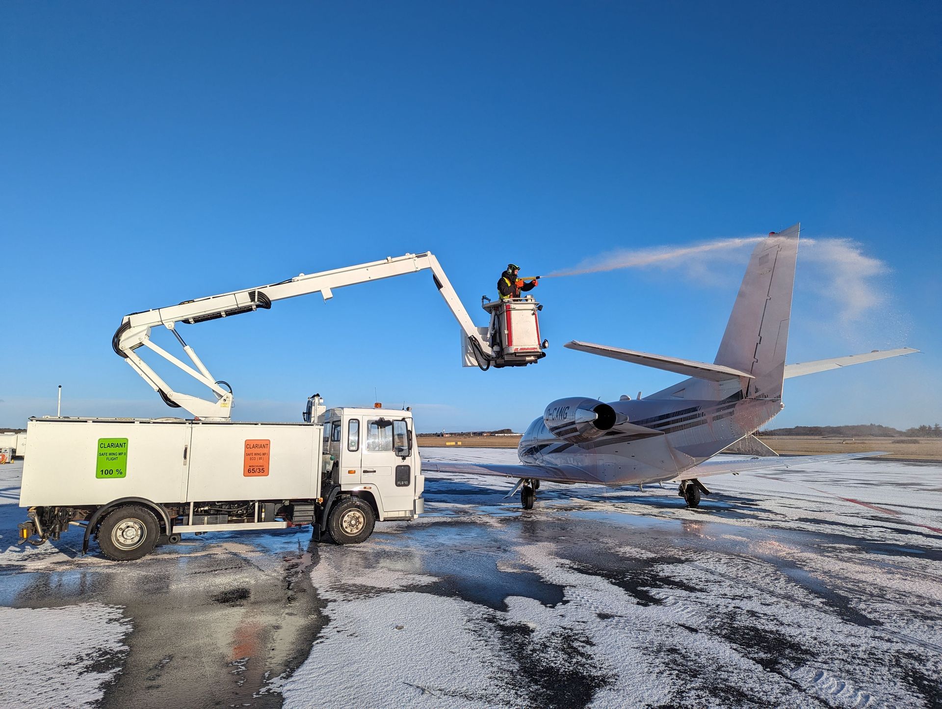 Private jet being deiced on a clear day at Sylt Airport, enhancing safety for flights.